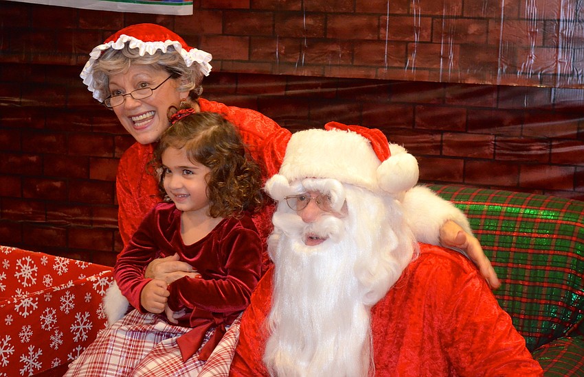 Mrs. Clause smiles with Haven Wood, 2, and Santa.