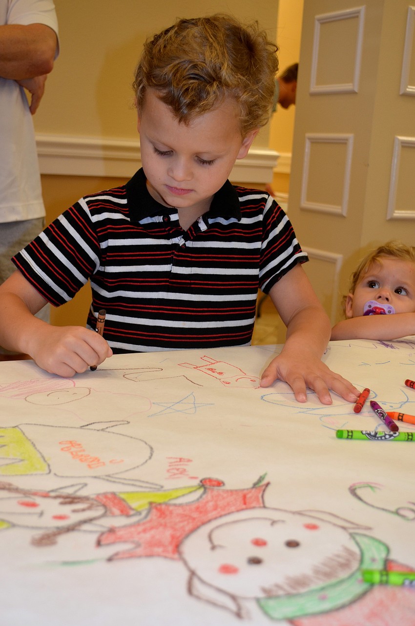 Five-year-old Owen Lockaby decorates a paper-lined table at the entrance.