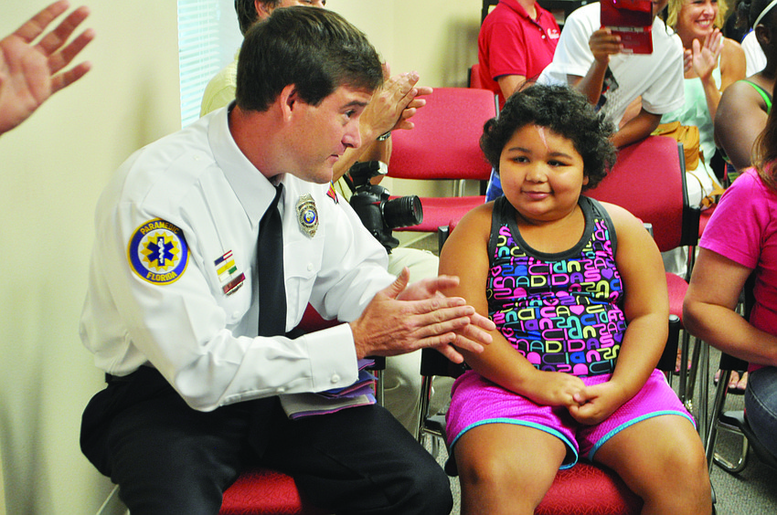 Firefighter/paramedic Brian Kolesa reunites with crash victim Onicka Patterson July 29, at the Longboat Key Fire Rescue North Station. Kolesa discovered the crash in Bradenton on his way to work and revived the girl, who was in cardiac arrest.