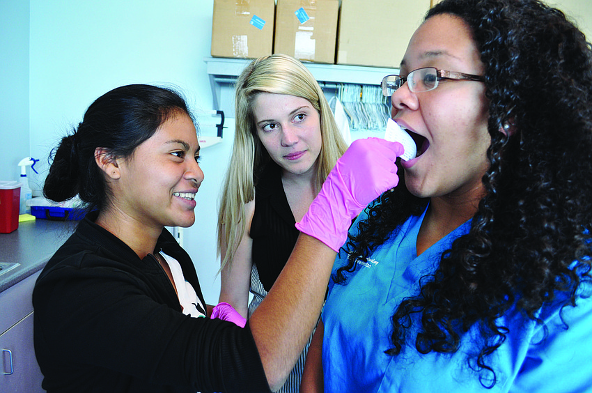 LECOM medical student Angelica Arellano measures the lateral movement of the jawbone of Maria Vivas, right, with the help of Kristen Balkam, center.