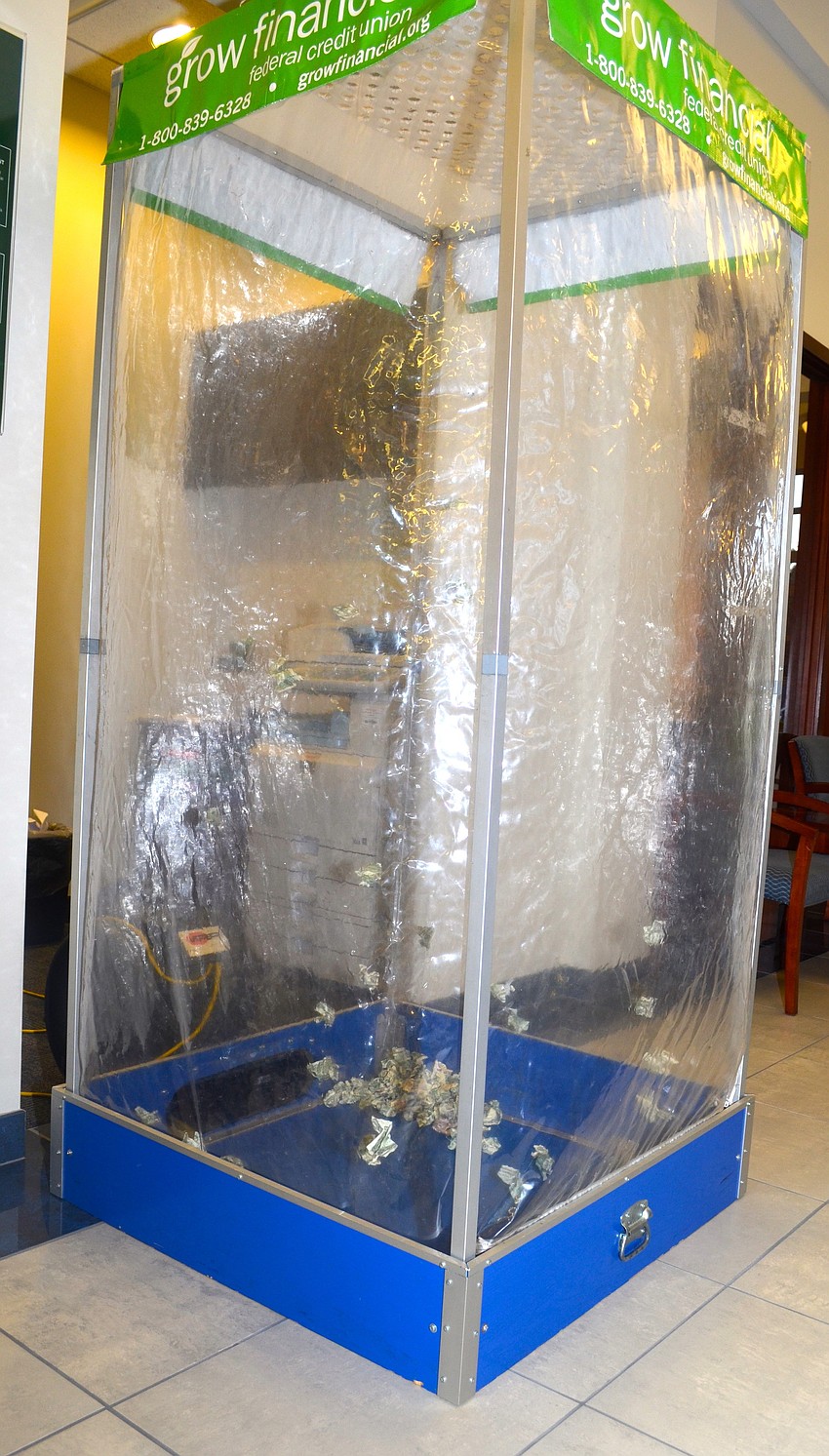 Winners of the raffle reach inside the plastic money booth to try to grab either $1,$5,$10 or $20 bills from the floating balls of cash inside.