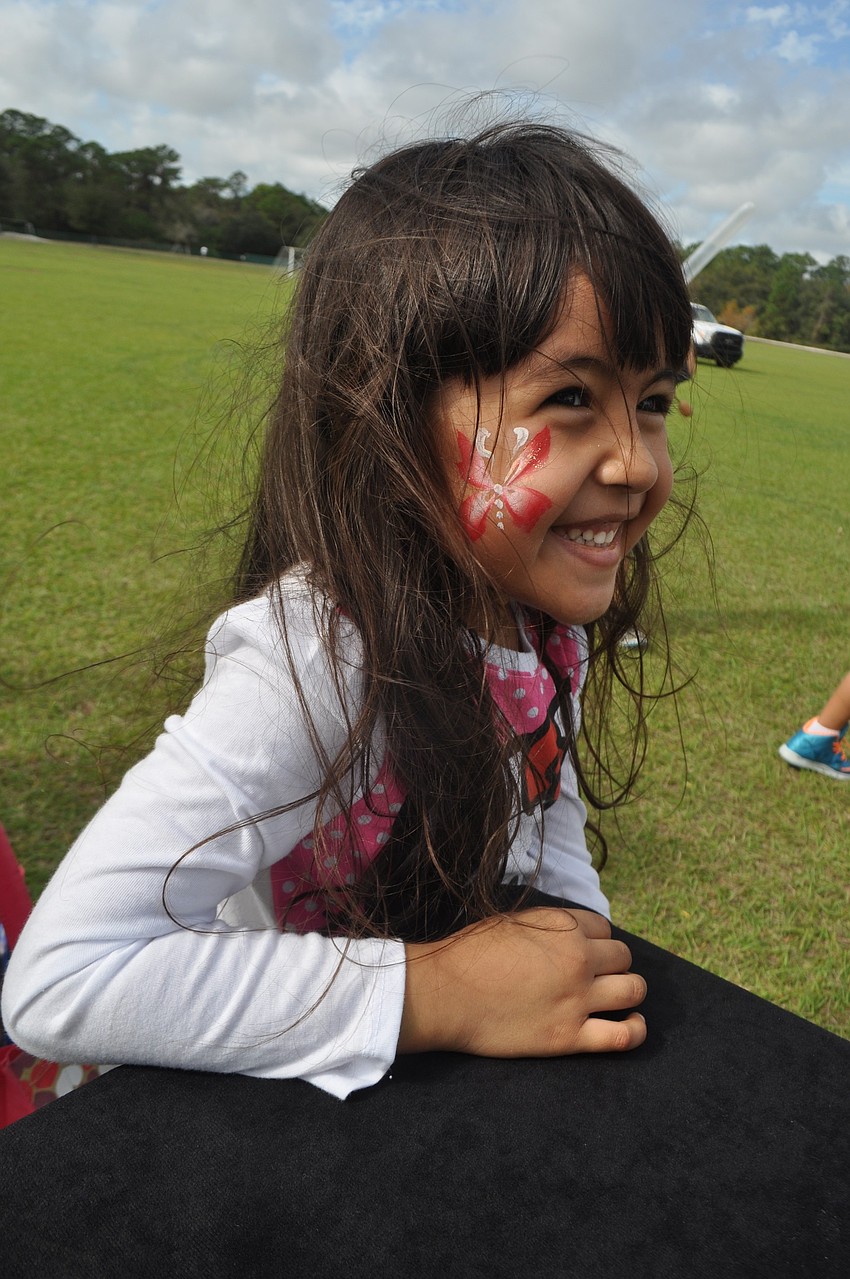 Grace Mendoza, 4, watches a balloon artist craft an animal for her.