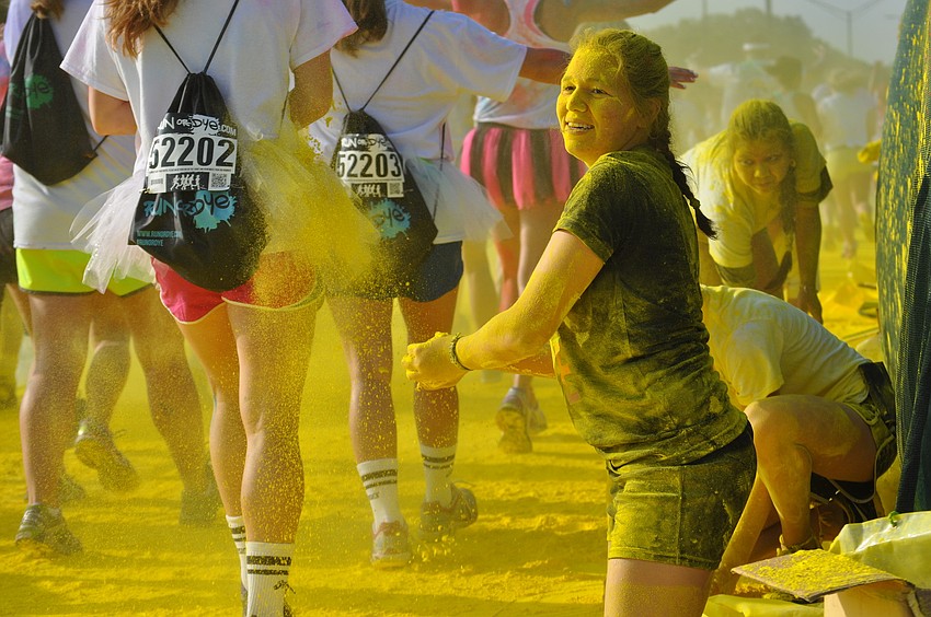 Volunteer Chelsea King, 16, throws yellow dye at runners as they pass.