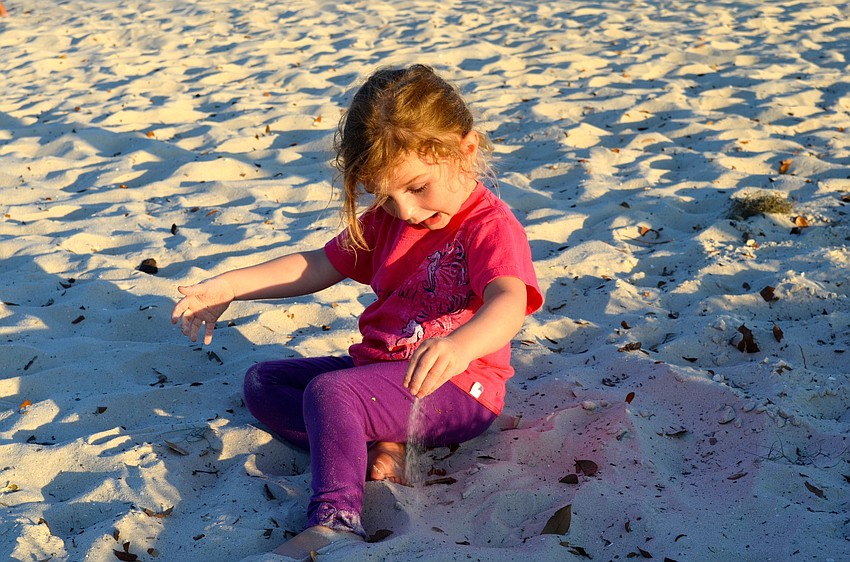 Three-year-old Sara Downs plays in the sand before the movie starts.