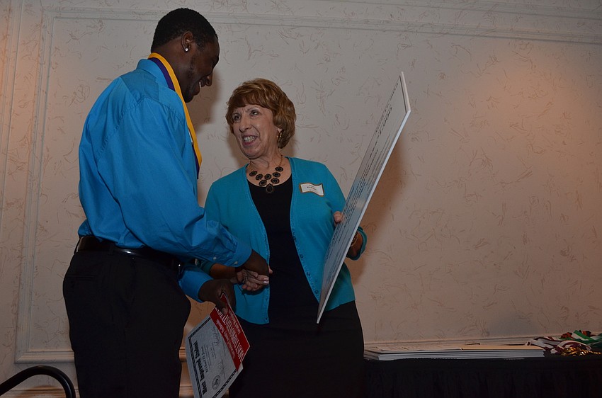 Sarasota County School Support Specialist Peni Riedinger awards Booker High School senior Michael Jones a scholarship for $1,000. Jones plans on playing football in the fall when he begins college.