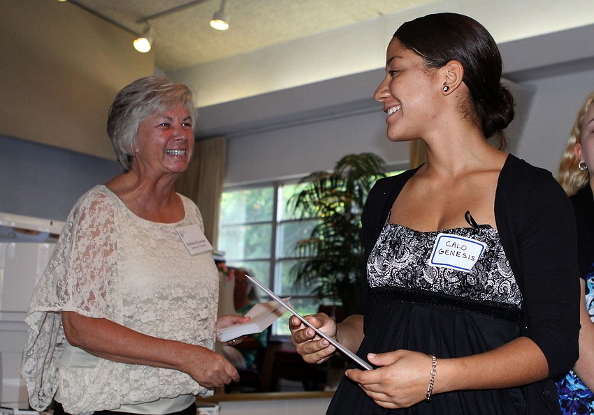 Barbara Koetsier hands Calo Genesis her scholarship envelope.