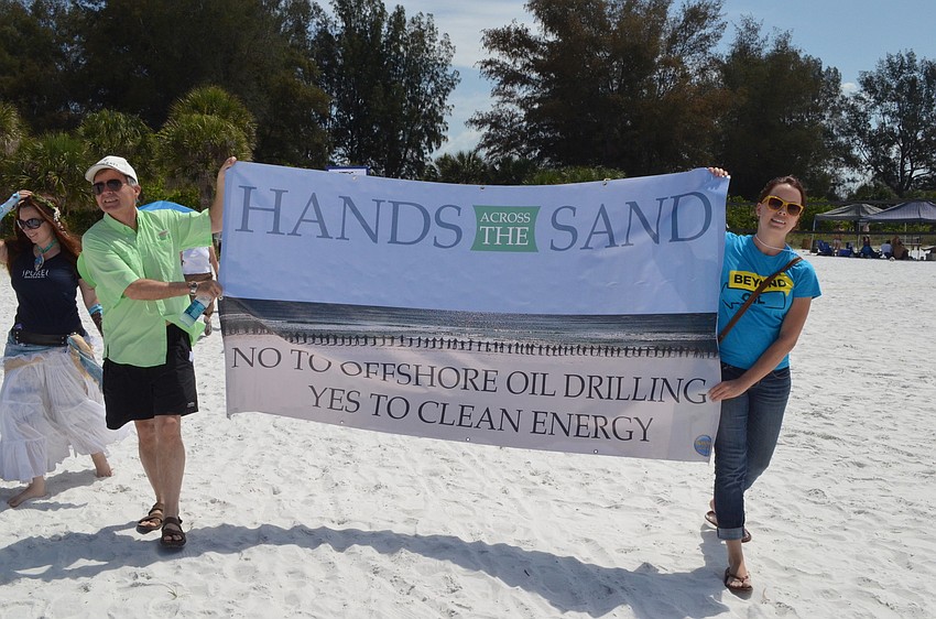 Charles Offer and Britten Cleveland hold up a sign as supporters walk to the shoreline.