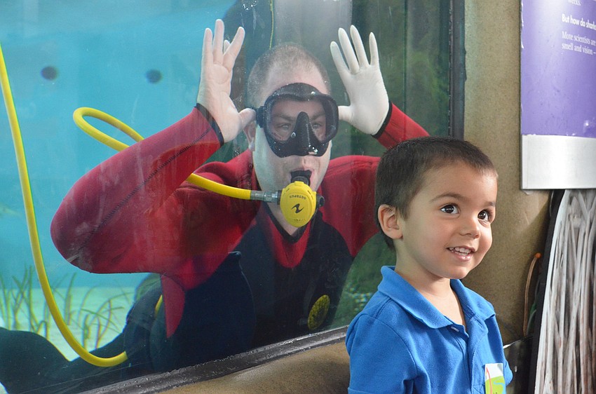 Nathan Alderman, 2, smiles as his mother takes a photo of him with the diver in the background.