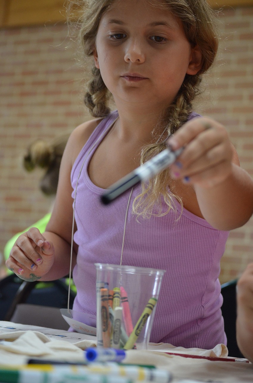 Caroline Jones, 7, chooses another color marker to color her mask.