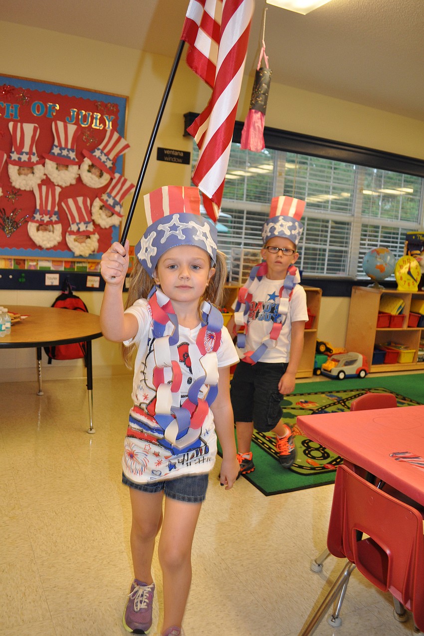 Five-year-old Tayler Snelling leads her classmates with the American flag.
