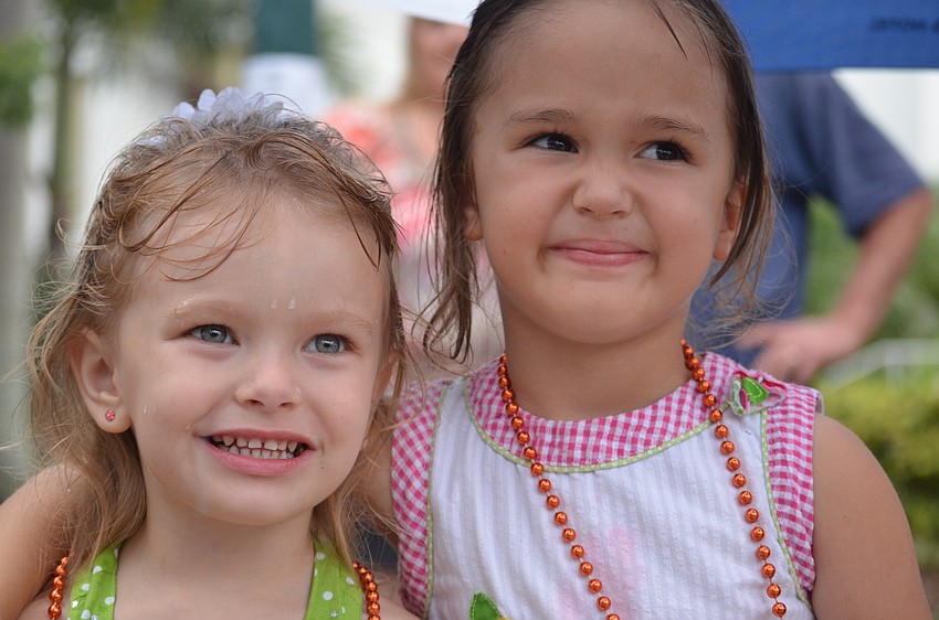 Emily Garris, 3, and Abigail Goulah, 5, watch the parade in the rain but still have a great time.