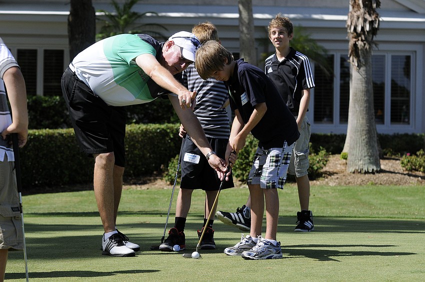 Lakewood Ranch High boys golf coach Dave Frantz helps 10-year-old Christian Kintz with his putting stance.