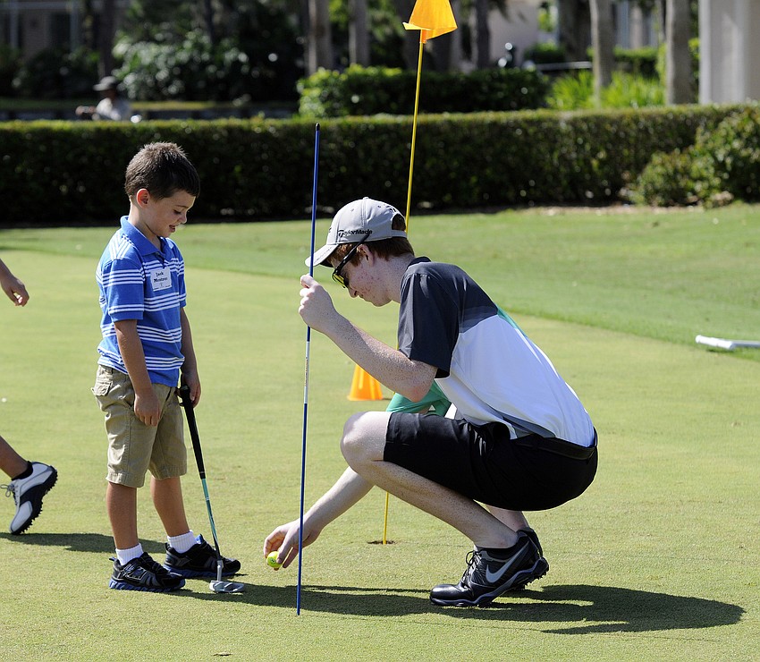 Five-year-old Jack Mentzer receives s important putting advice from Lakewood Ranch High sophomore Zach Rennie.