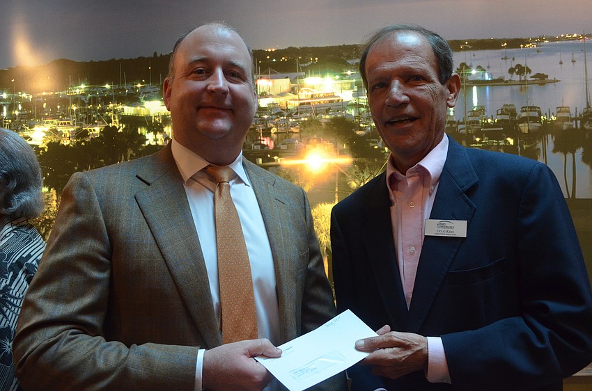 President of Michael Saunders & Company Drayton Saunders hands Doug Kerr of the Venice Symphony a grant check.