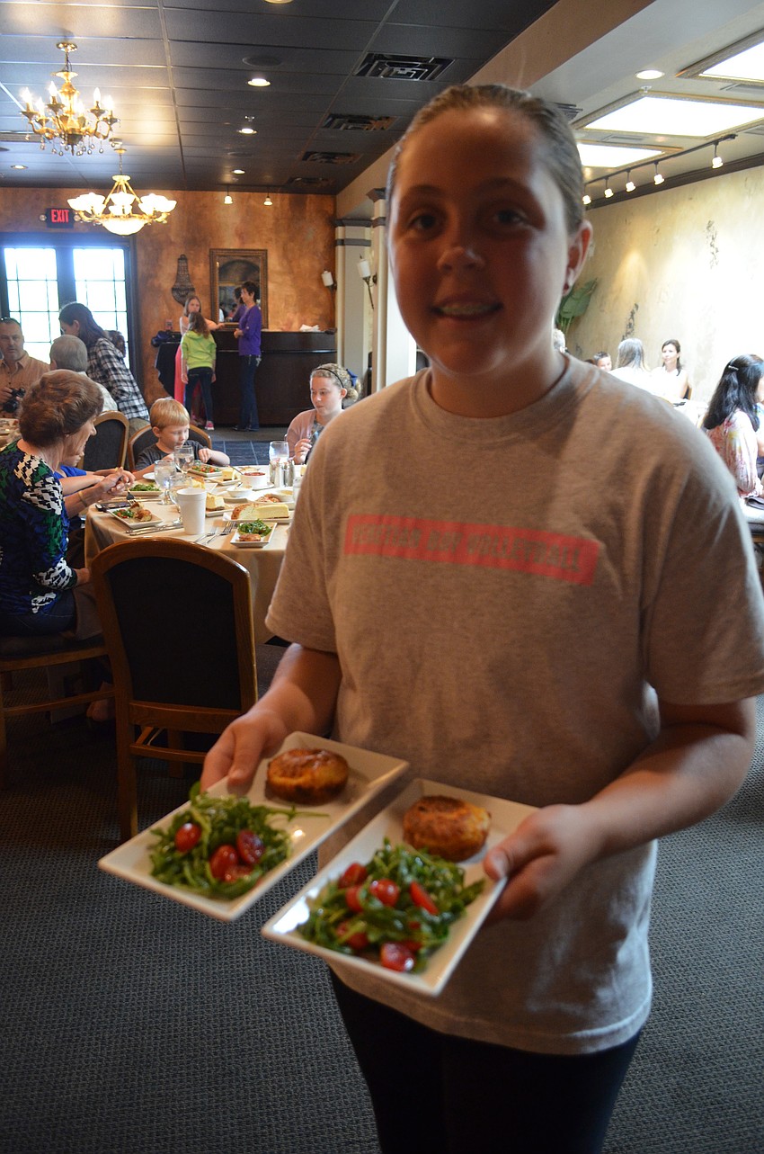 Emily Porter, 12, serves salad with cheese soufflÃ© to guests.