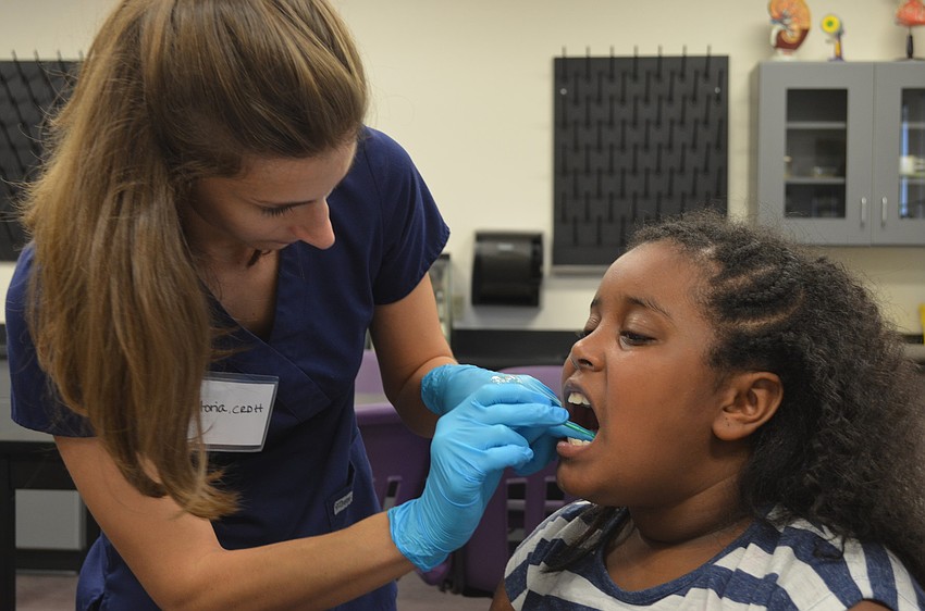 Dental Hygienist Victoria Bigham puts fluoride on 8-year-old Ruby Baldwinâ€™s teeth.