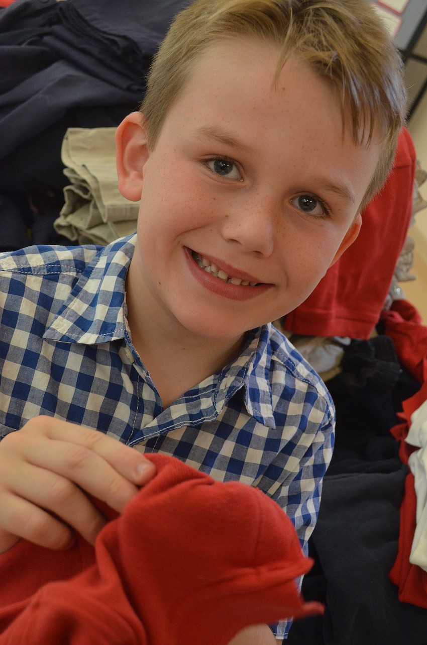 Auggie Toynton, 7, is entering second grade. He swaps his old uniform for one his size at the uniform swap.