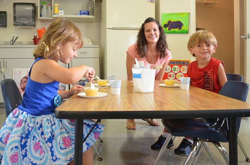 Tess D., Shawna Brown and Gavin B. enjoy snack time before the 3 year-olds begin making handprints.