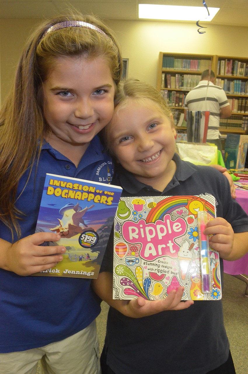 Sisters Briana DeStefano, 7, and Gianna, 6, choose books that their father purchases for them.