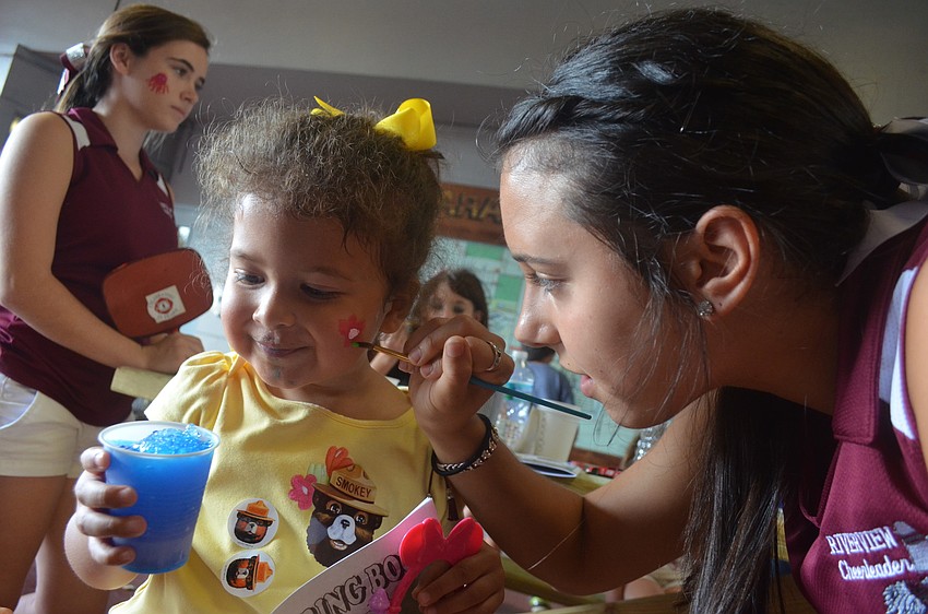 Riverview High School senior Lindsy Maglich, 16, paints a flower on 3 â€“ year old Isabella Moyaâ€™s face.