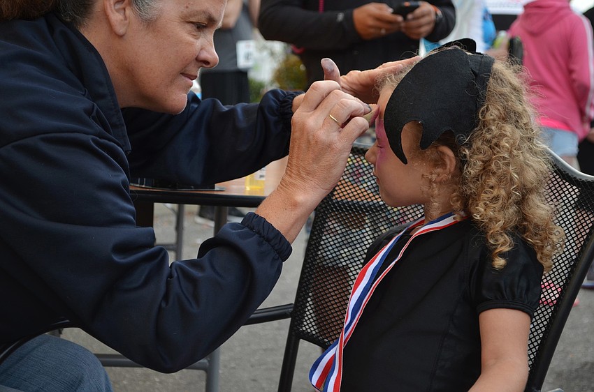 Sherry Jenkins from Amazing Character Entertainment paints Alexis Hutterâ€™s face at the Boo Run.
