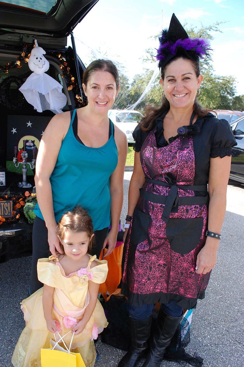 Victoria Cobb and her daughter, Abigail, 3, stopped for candy at the trunk of their friend, Tracy Fox.