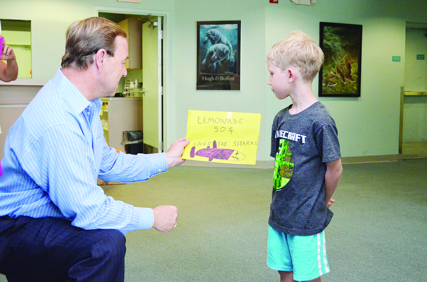 Emil Peterson, 6, meets with Mote Marine Laboratory & Aquarium Chief Advancement Officer Tom Waters to donate $50 in quarters he raised from a lemonade stand to help protect sharks.