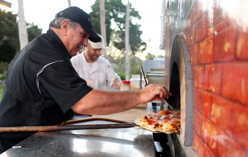 Frank Vespa, the owner of Goodfellas CafÃ© and Winery, checks on of the pizzas in the oven.