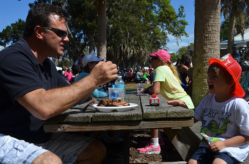 Tom Cail teaches son, Jaxon, how to eat ribs.