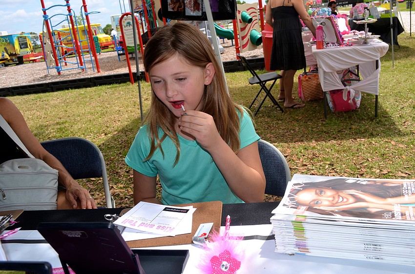 Jocelyn Freed tries on red lipstick at the Mary Kay booth.