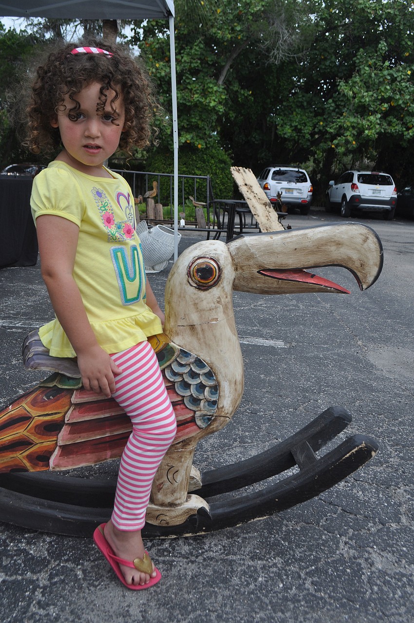 Teagan Ralph, 4, rides a rocking chair at the Vintage Vibe booth