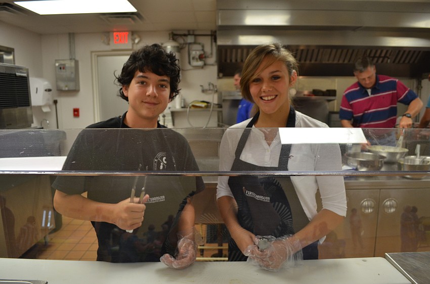 Justin Cupo and Ashley Waters serve breakfast to parishioners.