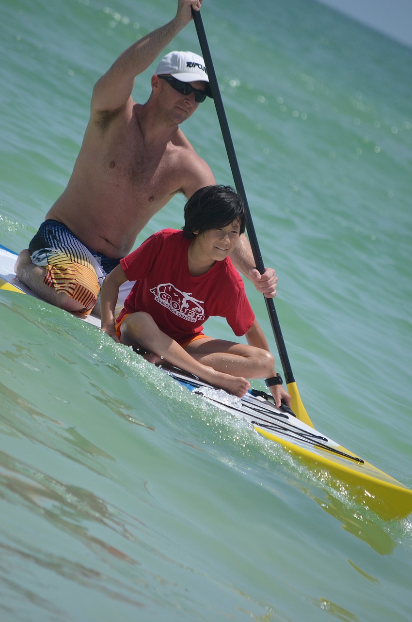 Sarasota firefighter and Hovie SUP volunteer Chris Kelly takes Peri Labonte out on a paddle board.