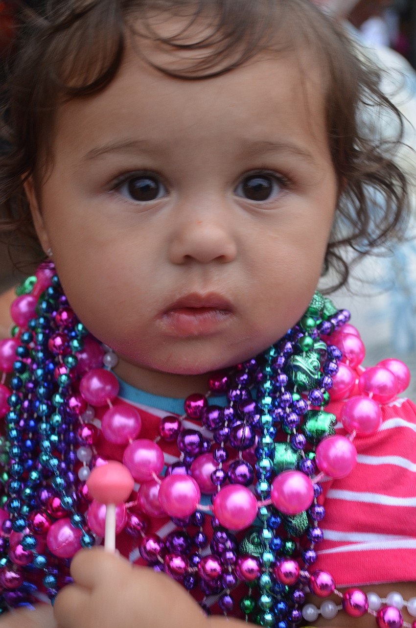 Mea Donahue, 15 months, collects beads and sucks on her lollipop during the parade.