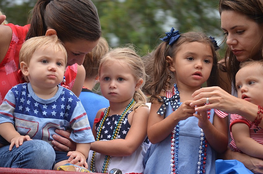 Sara Hauenstein with her children, Deacon and Brooklyn, and Amie Olivia with her children, Amara and Aria, ride the fire truck down Main Street.