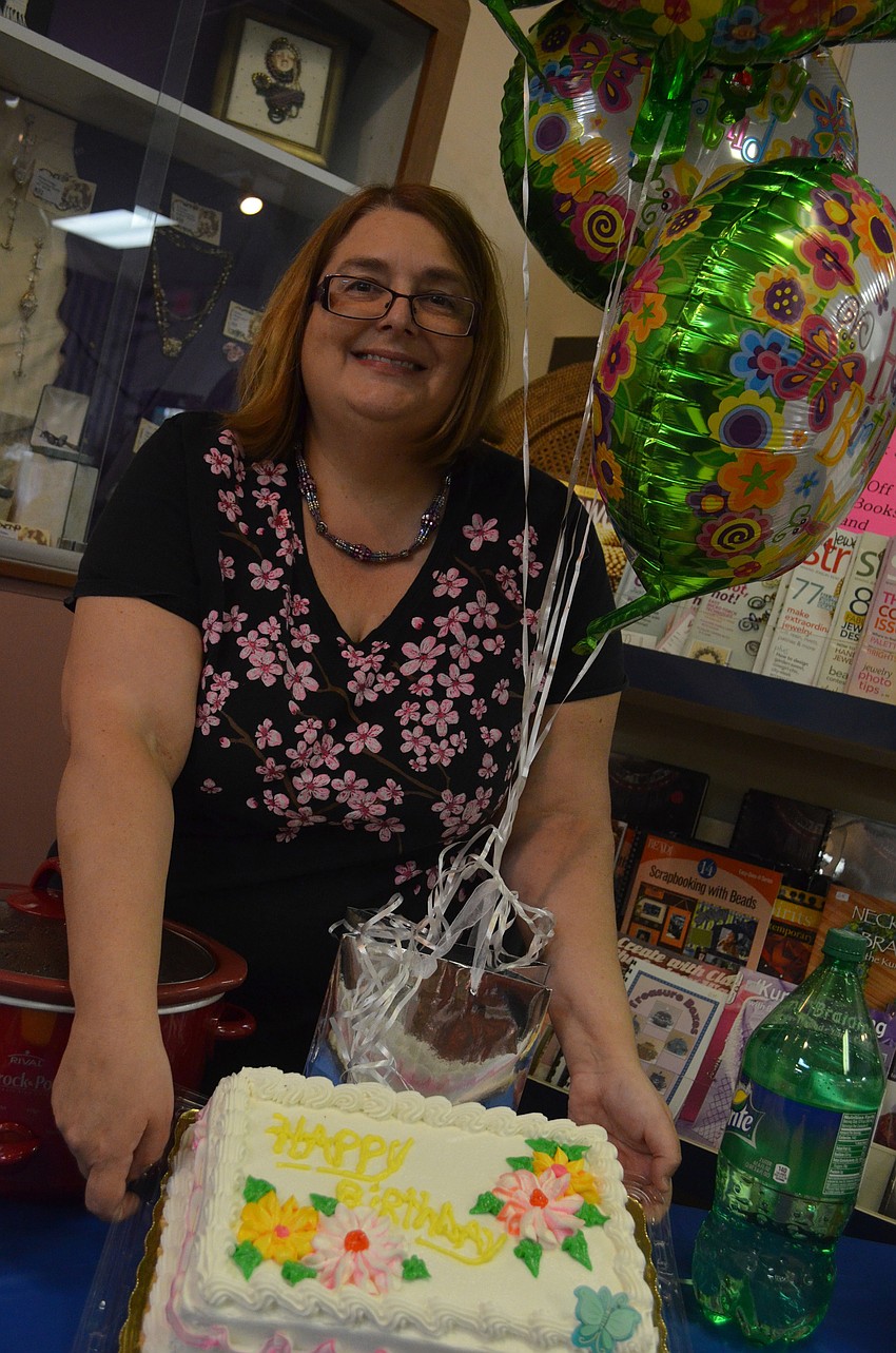 Karen Johnson holds up the birthday cake for the storeâ€™s 20th birthday.