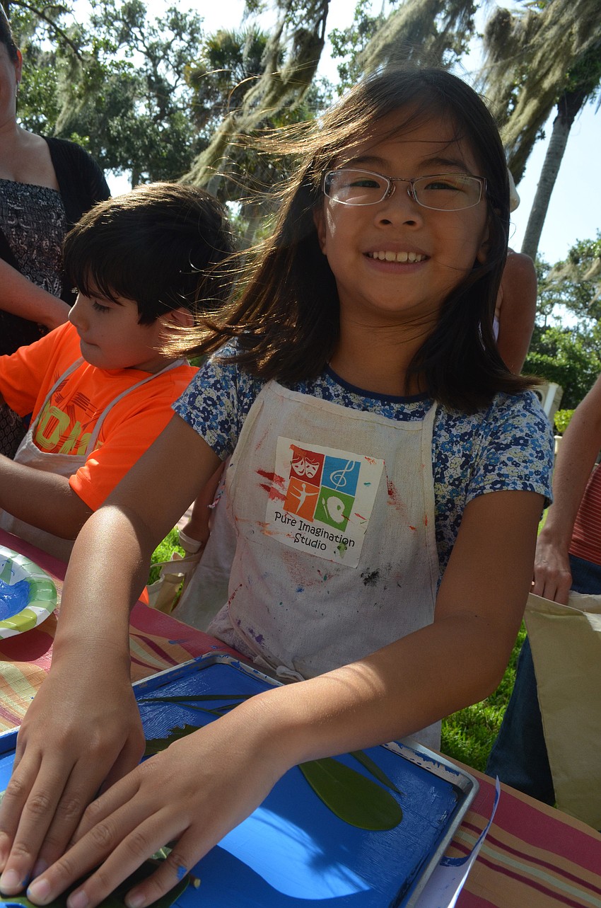 Grace Milton, 8, uses blue paint for her canvas bag.