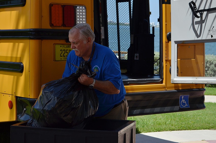 Bus driver Craig Taylor loads the backpacks into a school bus.