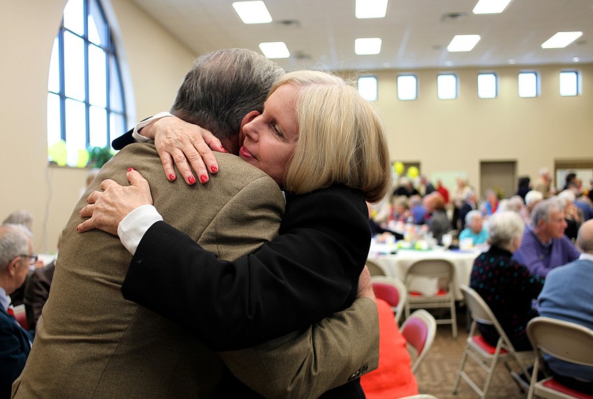 Debra McKenna hugs the Rev. Bruce Porter before the program.