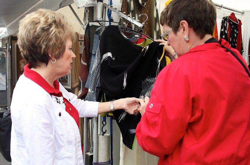 Rose King and Cheri Schloerke look through Shekina Designsâ€™ hand-painted silk clothing.