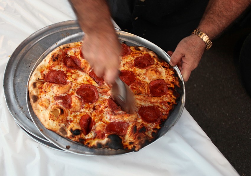 Frank Vespa cuts a pepperoni pizza fresh out of the oven.