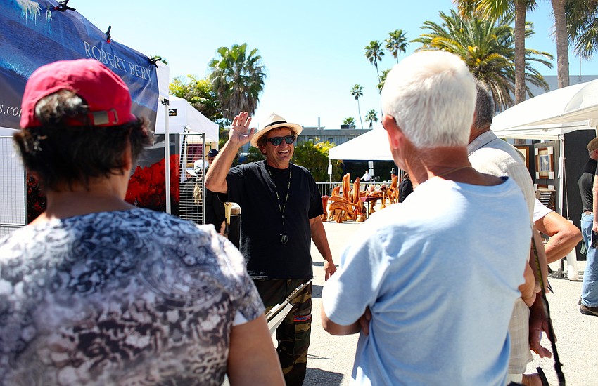 Robert Bery jokes with a small crowd at his booth.
