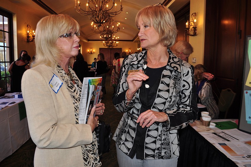 Karen Martin learns about Dining for Women from Beth Palmer, who also represented the Womenâ€™s Resource Center.