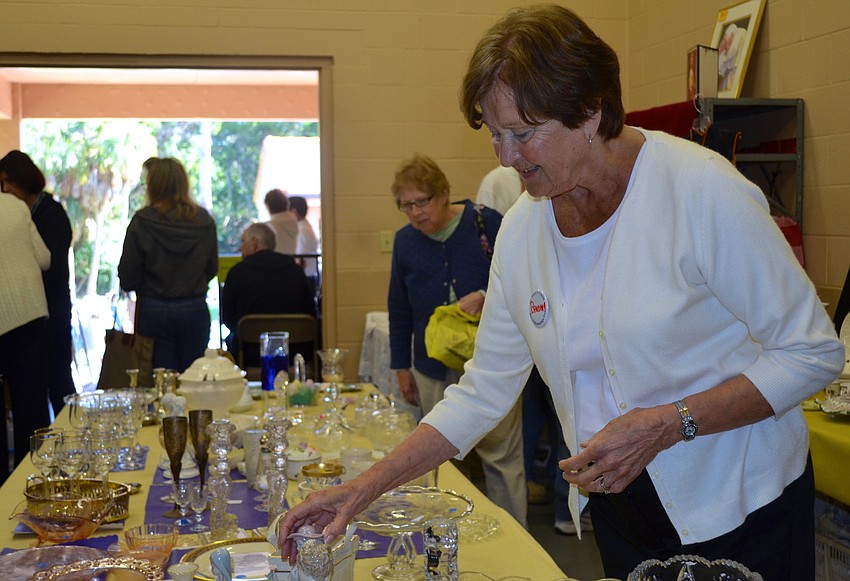 Barbara Miller rearranges the glassware during the sale.