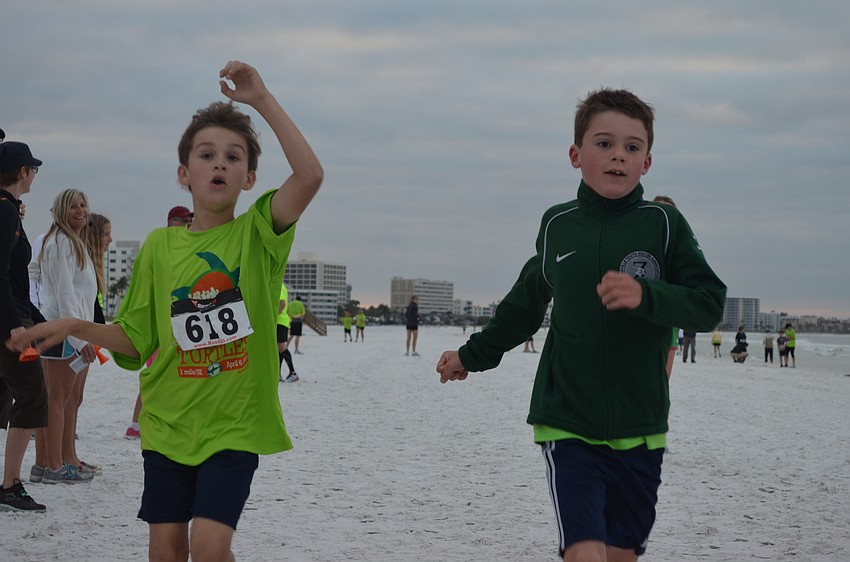 Camden Wozniak and Charlie Fisher cross the finish line at the 1 â€“ mile â€“fun â€“run/walk.