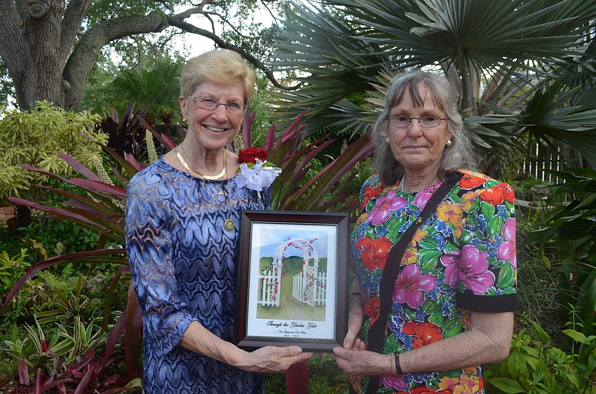 Sue Angle and Ruth Linsley hold up the painting Linsley painted for Angle.