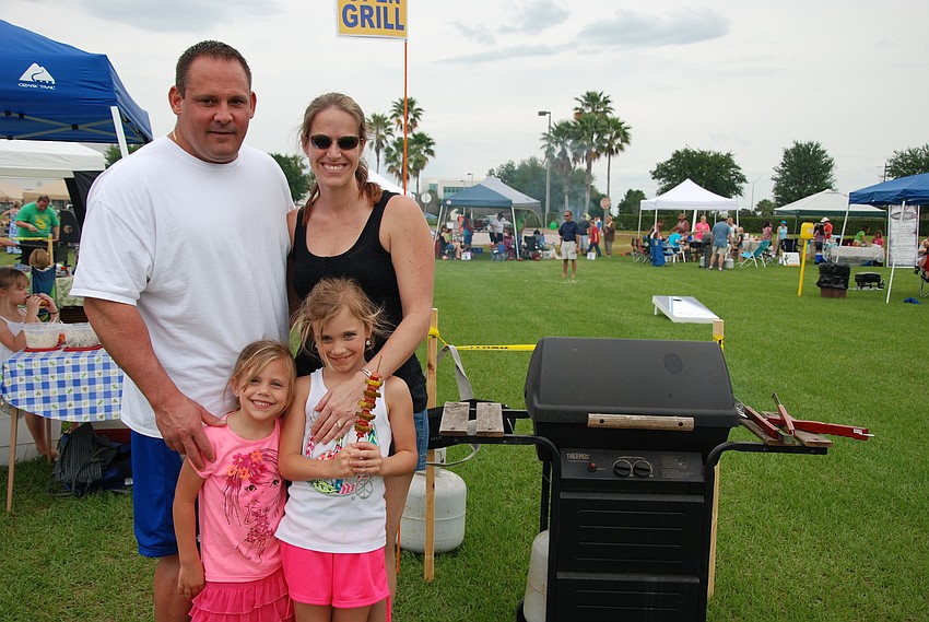 George, Heather, Morgan, and Natalie Fellows gather together for a family photo while cooking on an open grill.
