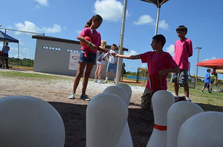 Luna Reitz pays in baseball bucks to play the bowling game.