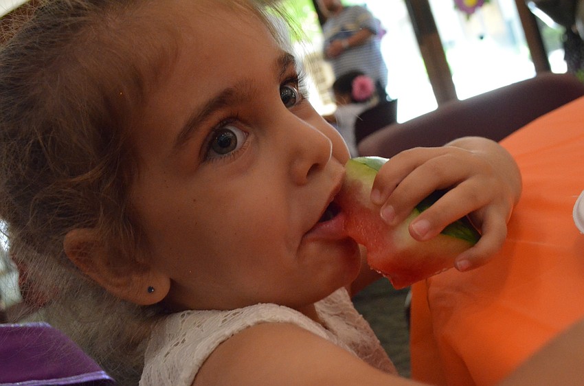 Mila Saba bites into a cool watermelon on a hot day. Mila came to see her sister Lily sing and to play at the Butterfly Ball.