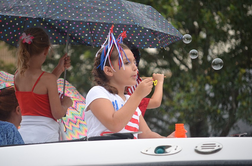 Children blow bubbles as they ride in boats in the parade.